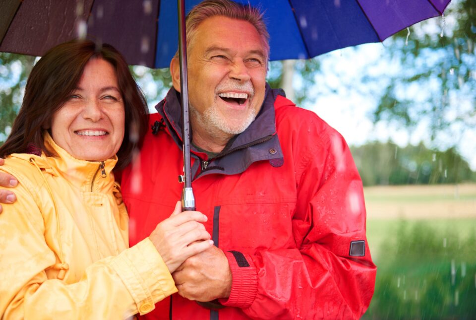 Happy senior couple standing in the rain under an umbrella